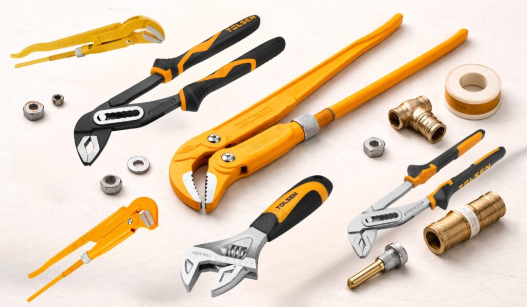 Tolsen klešta različitih tipova položena na svetlo bež pozadini, uključujući papagajke, vodoinstalaterska klešta i podesivi ključ, sa jasno vidljivim ivicama i detaljima alata